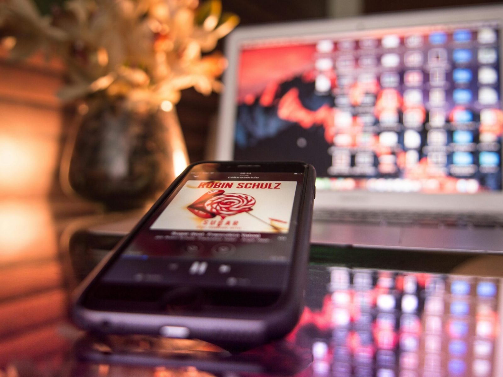 Modern workspace featuring a smartphone and laptop with vibrant lighting and reflections.