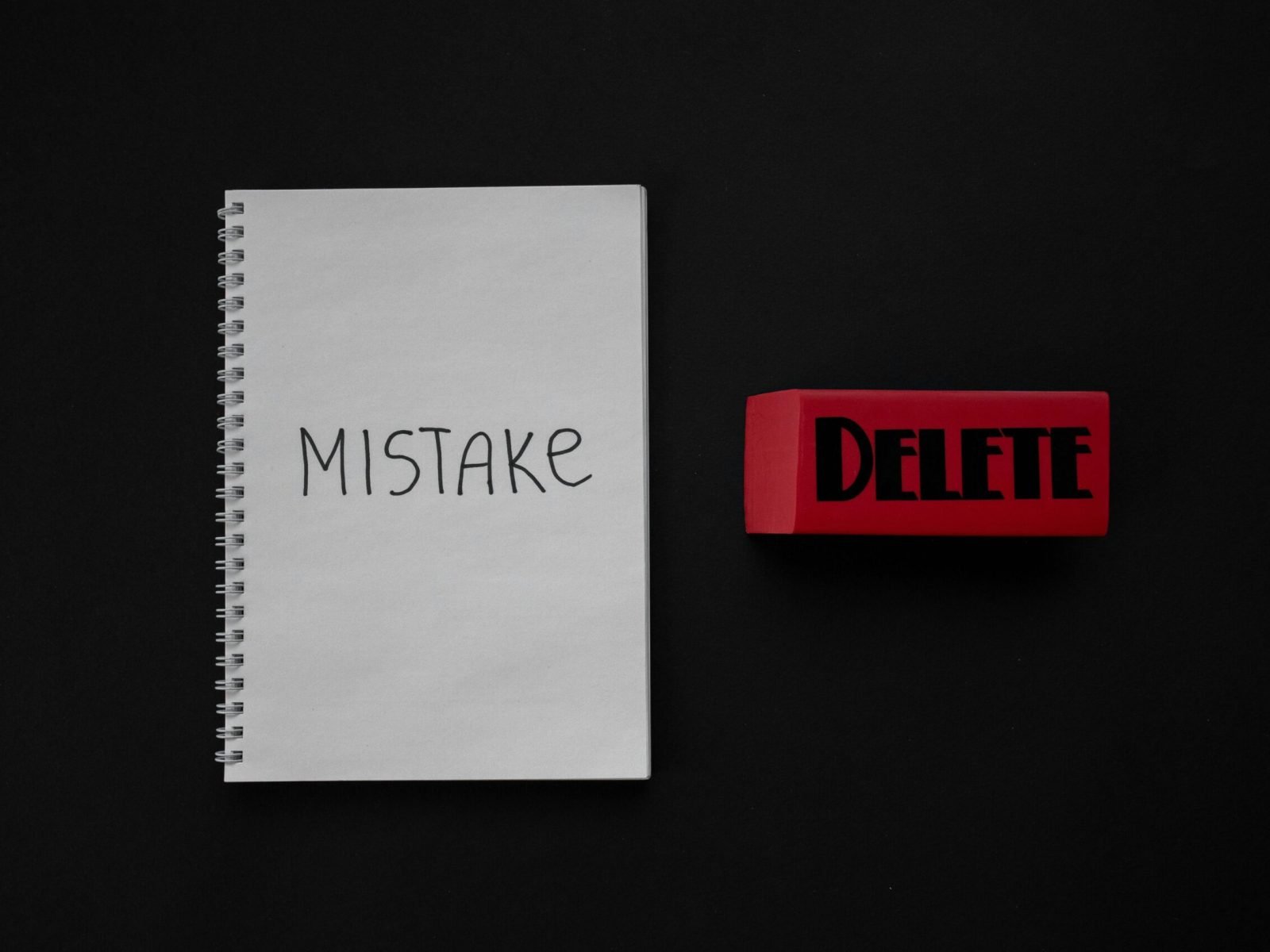 Notebook labeled 'Mistake' next to a red delete eraser on a dark background.
