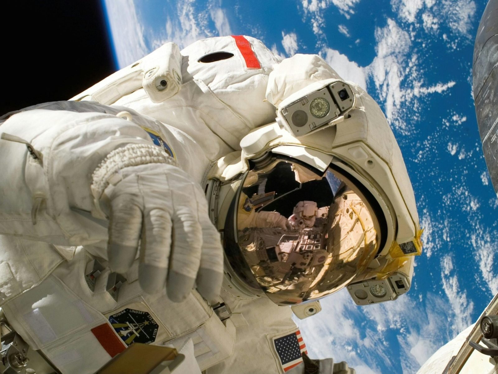 Astronaut floating in space during a spacewalk, visible Earth in the background.